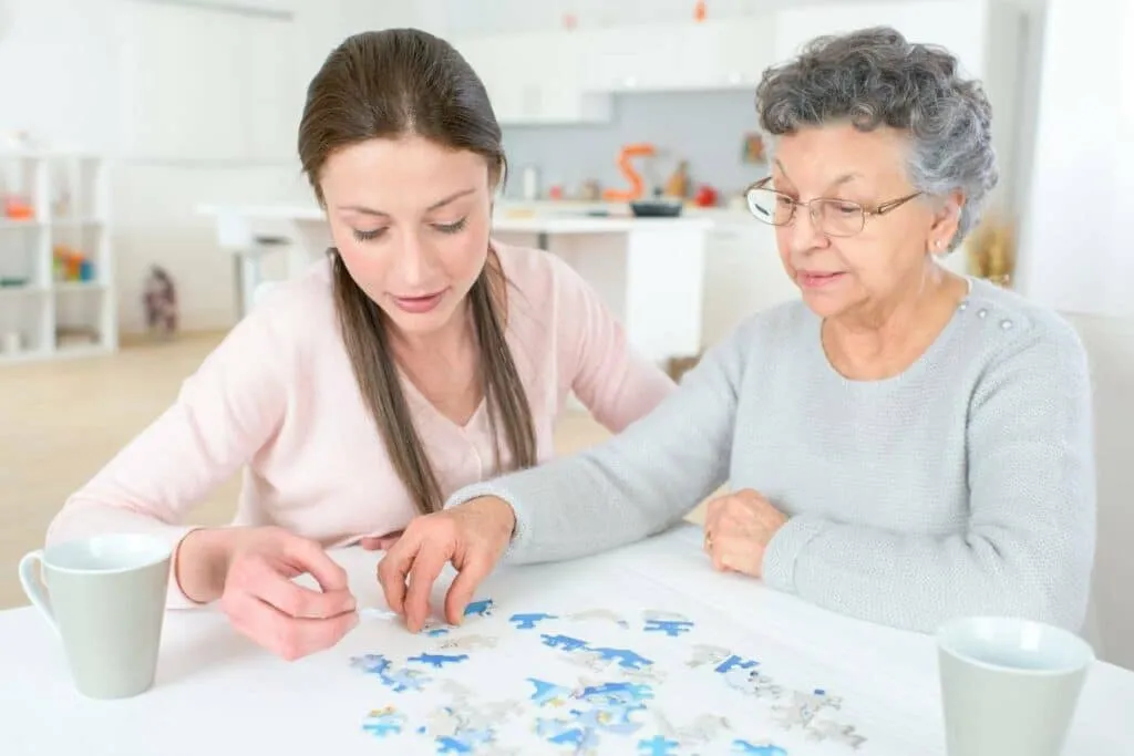 An older woman enjoying a jigsaw puzzle at home with her regular Flexicare carer