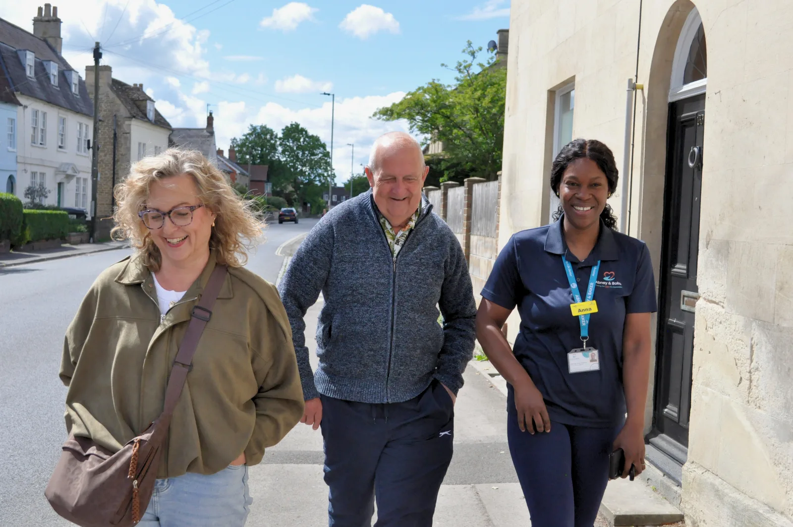 An Abney & Baker carer accompanying an older man on a walk along a residential street.
